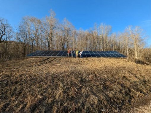 Group standing by large solar panel